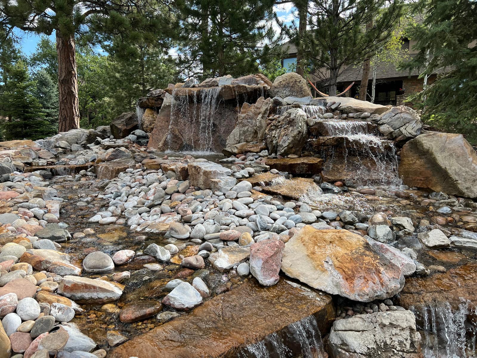 Boulder waterfalls cascading into a rock stream among pines