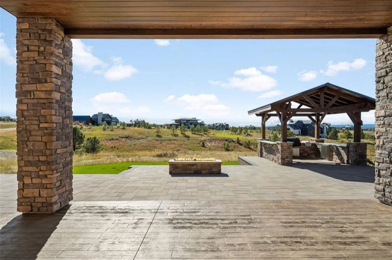 Covered patio with stone columns overlooking a timber pavilion and open views